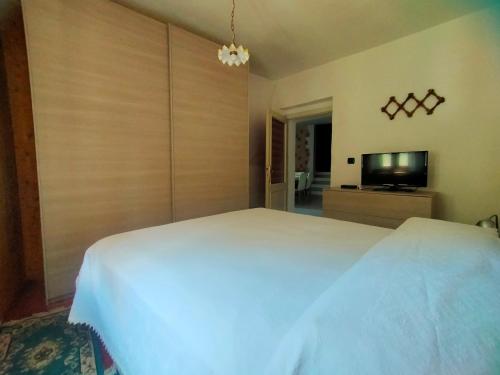 a bedroom with a white bed and a flat screen tv at La Quiete in Ponte Caffaro