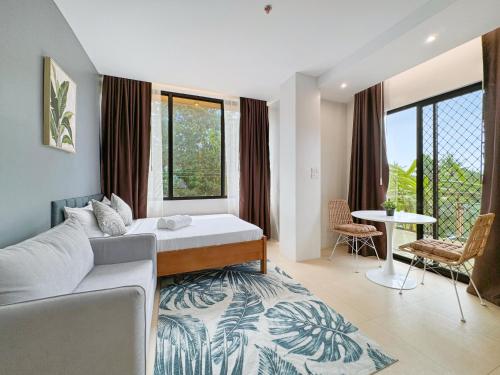 a bedroom with a bed and a table and some windows at El Jardin Residences in Panglao Island