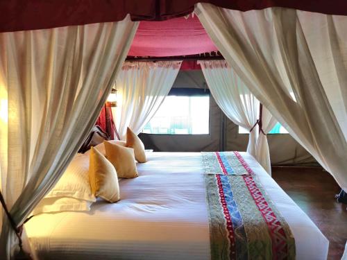 a bedroom with a large bed with curtains at Kirawira Serena Camp in Handajega
