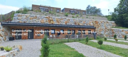 ein Gebäude mit einer Steinmauer und ein Gebäude in der Unterkunft Tiny Apartments by Timo's Camp in Nöchling