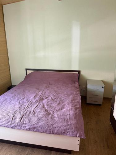 a bedroom with a bed with a purple blanket at Будинок на Дніпрі in Kozin