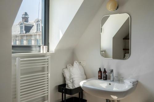 a white bathroom with a sink and a mirror at A Place Antwerp - Boutique Suites & Flats - Vrijdagmarkt 1 in Antwerp