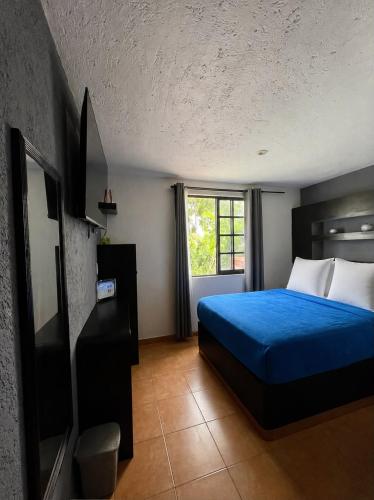 a bedroom with a blue bed and a window at Hotel Real Campestre Tepetoci in Tepexi del Río