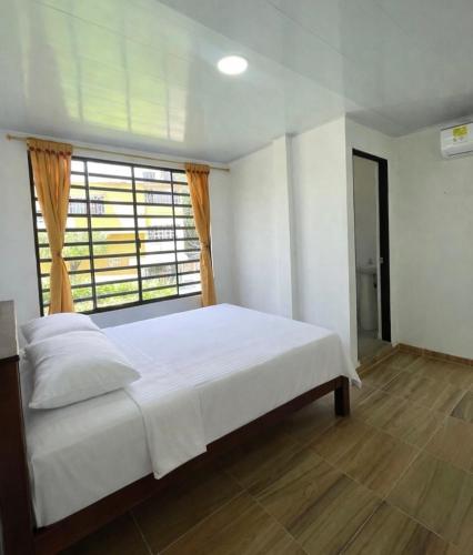 a bedroom with a white bed and a window at Apartamentos El Remanso in Mariquita