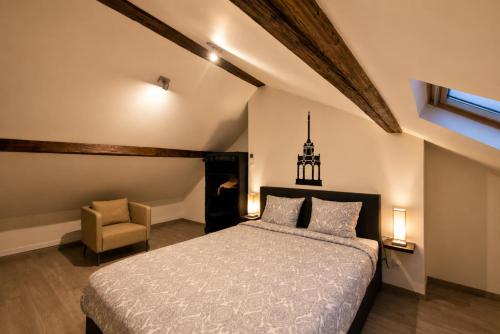 a bedroom with a large bed and a chair at Les Suites de Nanesse in Liège