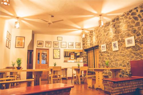 a restaurant with wooden tables and a stone wall at Wildernest in Thekkady