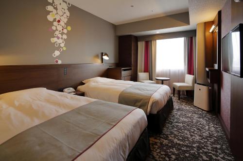 Habitación de hotel con 2 camas y TV de pantalla plana. en Hotel Monte Hermana Fukuoka, en Fukuoka