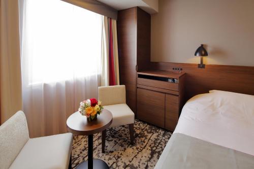 a hotel room with a bed and a table with flowers at Hotel Monte Hermana Fukuoka in Fukuoka