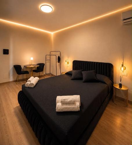 a bedroom with a black bed with towels on it at Le Charme Luxury Suite in Patti