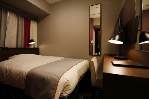 a bedroom with a bed and a desk and a mirror at Hotel Monte Hermana Fukuoka in Fukuoka