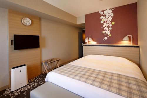 a hotel room with a bed and a tv at Hotel Monte Hermana Fukuoka in Fukuoka