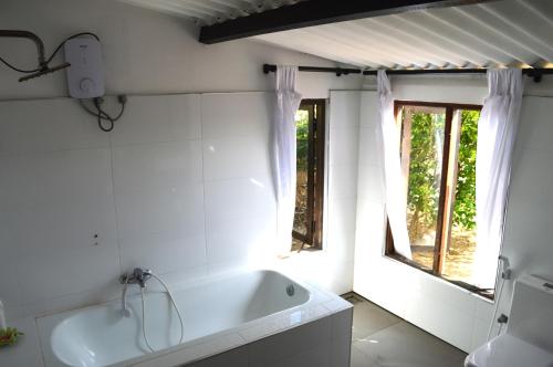a white bathroom with a tub and a window at Azeer's in Arugam Bay