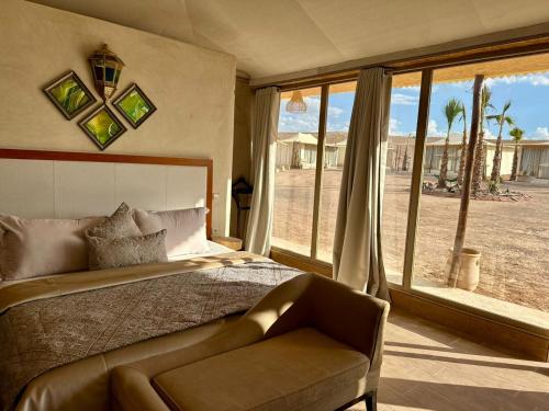 a bedroom with a bed and a chair and a window at Yes We Camp Agafay Luxury Khaïma & Restaurant - Spa in El Karia
