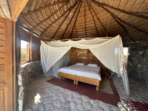 a bedroom with a bed in a straw roof at Manga Bay Lodge in Toliara