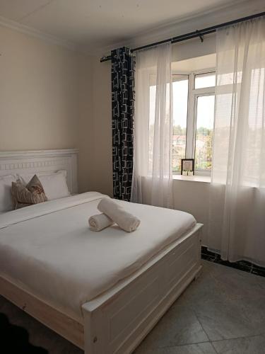 a bedroom with a large white bed with a window at Mura suites homes in Nakuru