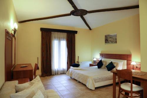 a bedroom with a bed and a desk and a window at TSIGOURA VERDE RESORT in Mikrós Prínos