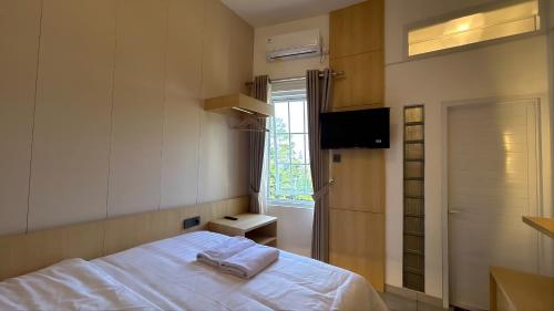 a bedroom with a bed and a window and a television at Naeera Inn Wonosobo Dieng in Kalibeber