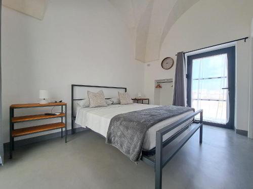 a white bedroom with a bed and a window at Casina Pompiliano in Nardò