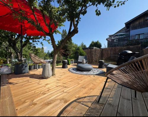 a wooden deck with chairs and a red umbrella at Le Refuge in Margencel