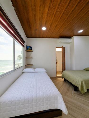 a bedroom with two beds and a large window at Suite frente al Mar con Acceso Directo a la Playa in Ballenita