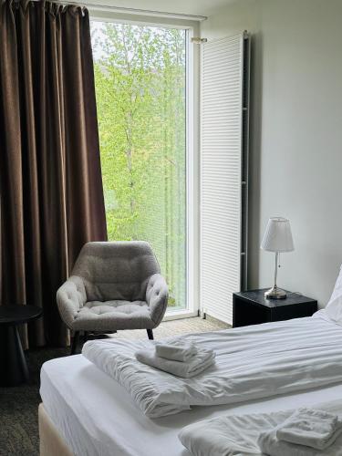 a bedroom with a chair and a bed and a window at Hótel Bifröst in Bifrost
