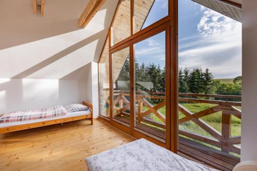 a room with a bed and a large window at Ad Matrem in Zubrzyca Dolna
