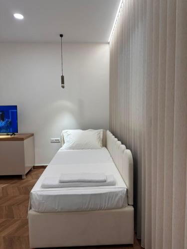 a white bed in a room with a wall at Zac's Rooms in Dukat