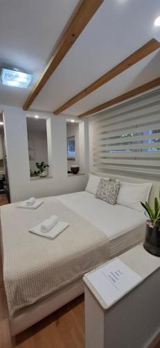 a white bedroom with a large bed and a table at Guest House NO 13 in Mostar