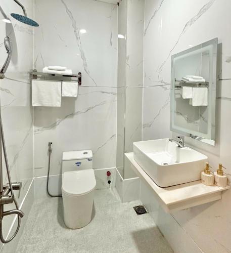 a white bathroom with a sink and a toilet at Phú Gia Hotel 464 Nguyễn Văn Linh in Ho Chi Minh City