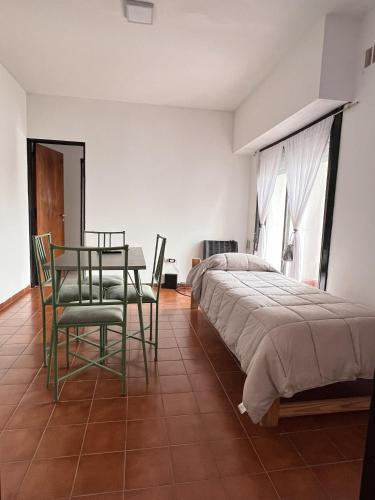 a bedroom with a bed and a table and chairs at Olivos Lujan in Luján