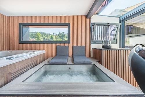 a bathroom with a tub with two chairs in it at Casa do primo Zeca in Ponte da Barca