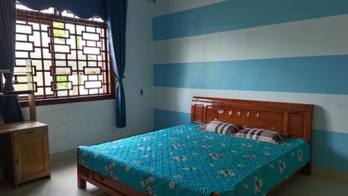 a bedroom with a bed with a blue and white stripes at Tay Na Bon Homestay in Ha Giang