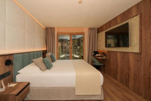 a bedroom with a bed and a desk and a window at Hotel Princesa Parc Excellence in Arinsal