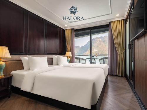 two white beds in a room with a window at Halora Kairos Cruise in Ha Long