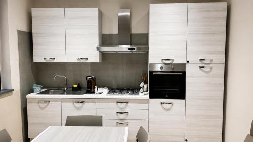 a kitchen with white cabinets and a black appliance at Casa RUDOM in Aci SantʼAntonio