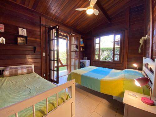 a bedroom with two beds in a room with wooden walls at Paz na Serra Teresopolis Pet Friendly in Teresópolis