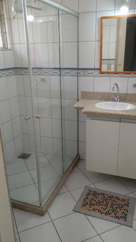 a bathroom with a glass shower and a sink at Hospedagem do TCHÊ in Vila Velha