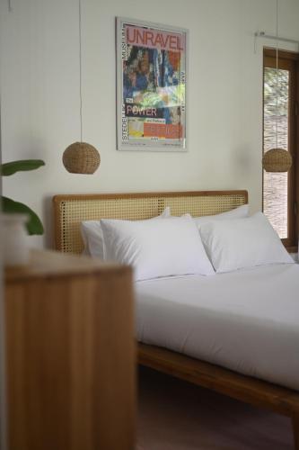 a bed with white pillows and a poster on the wall at Mayava Villa in Ahangama