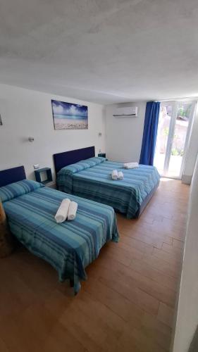 two beds in a room with blue and green sheets at PortoPollo SurfHouse C in Barrabisa
