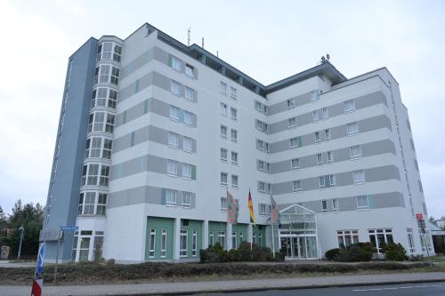 a large white building with flags in front of it at ACHAT Hotel Schwarzheide Lausitz in Schwarzheide