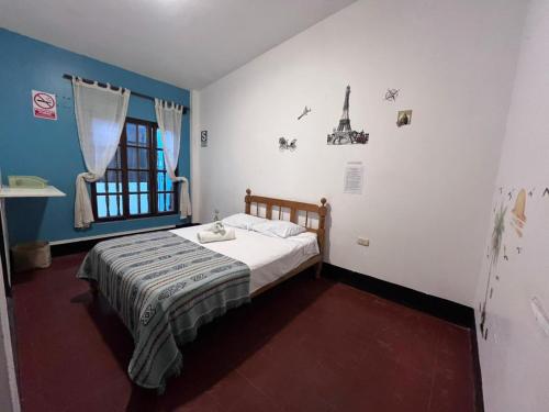 a small bedroom with a bed and a window at Wayra Hostel Huanchaco in Huanchaco