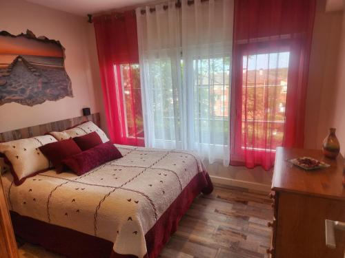 a bedroom with a bed with red curtains and windows at Apartamento Riberuca Playa in Suances