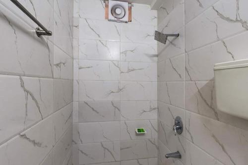 a bathroom with a shower with white marble tiles at Hotel Sky in Dwarka