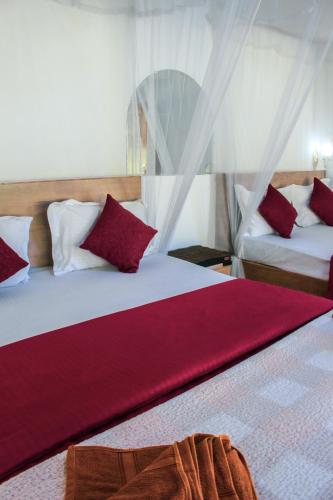 ein Schlafzimmer mit zwei Betten und roten und weißen Kissen in der Unterkunft Trailside Ella-Your Gateway to Ella Rock in Ella
