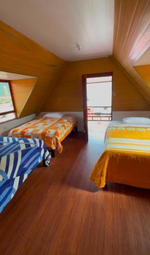 a attic room with two beds and a window at La Casita de Merme in Oxapampa