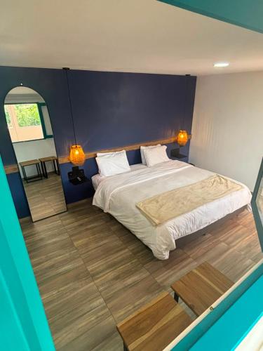a bedroom with a large bed and a blue wall at Hotel Tumbaga 88 in Salento