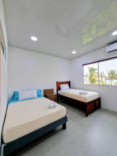 two beds in a room with a window at Suite Meridiano Direct Beach Access y AC in Ballenita
