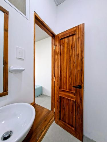 a bathroom with a sink and a wooden door at Suite Meridiano Direct Beach Access y AC in Ballenita