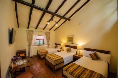 a hotel room with two beds and a table at San Agustin Monasterio de la Recoleta in Urubamba