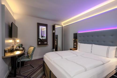 a hotel room with a large white bed and a desk at Premier Inn Koblenz City in Koblenz